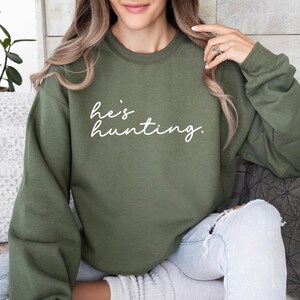 a woman sitting on a couch wearing a green sweatshirt