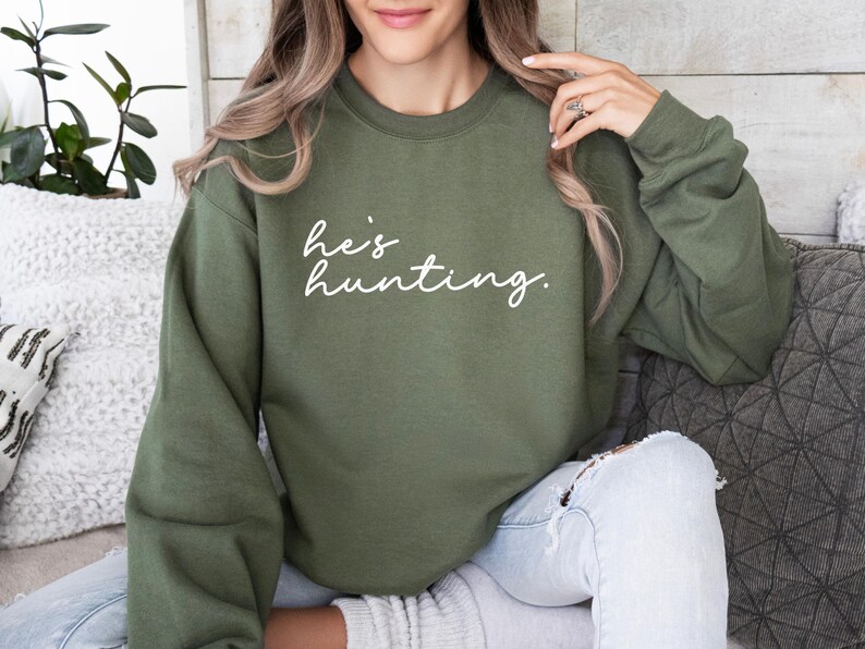 a woman sitting on a couch wearing a green sweatshirt
