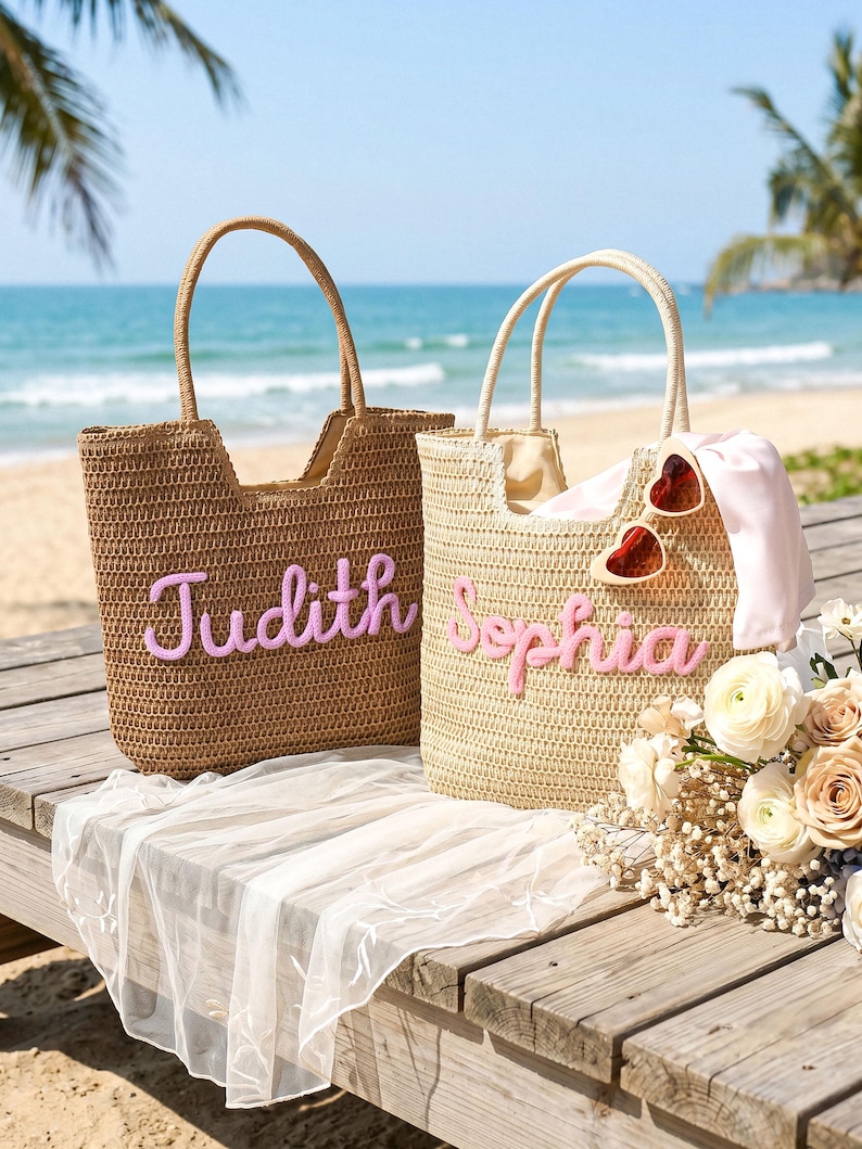 May include: Two woven straw tote bags with top handles. The left bag is brown with the name Judith in pink script. The right bag is beige with the name Sophia in pink script, featuring heart-shaped sunglasses and a light pink fabric draped inside.
