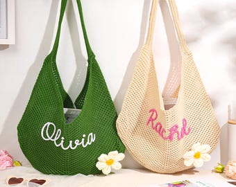 May include: Two handmade crochet tote bags. One is green with the name "Olivia" embroidered in white. The other is beige with the name "Rachel" embroidered in pink. Each bag has a white flower accent.