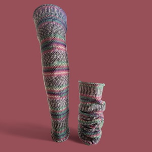 May include: Two knitted leg warmers and a matching ankle warmer. The leg warmers are long and patterned with a diamond design, and the ankle warmer is scrunched. The colours include shades of grey, green, pink, and purple.