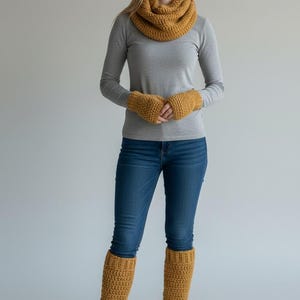 May include: A mustard yellow chunky knit infinity scarf, matching fingerless gloves, and ribbed leg warmers. The set is worn with a long-sleeved gray shirt, blue denim jeans, and white sneakers. The knit accessories feature a thick, textured yarn.