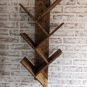 May include: A rustic wooden wall shelf with a unique angled design. The shelf has five shelves that are angled to create a V-shape. The shelf is made of reclaimed wood and has a natural finish.