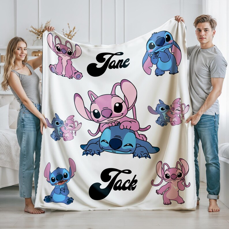 K&ouml;nnte beinhalten: Eine wei&szlig;e Decke mit Cartoon-Figuren in Blau- und Rosat&ouml;nen. Die Decke tr&auml;gt die Namen "Jane" und "Jack" in schwarzer Schrift. Die Decke wird von zwei Personen gehalten.