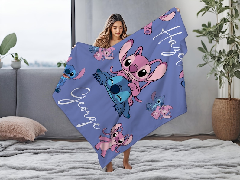 K&ouml;nnte beinhalten: Eine periwinkleblaue Decke mit den Zeichentrickfiguren Stitch und Angel in verschiedenen Posen. Die Decke tr&auml;gt die Namen "George" und "Hayley" in wei&szlig;er Schrift. Die Decke besteht aus einem weichen Material.