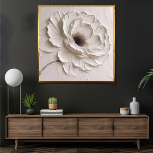 May include: A framed canvas print of a white flower with a textured, 3D effect. The flower is the focal point of the image, with a white background and a gold frame.