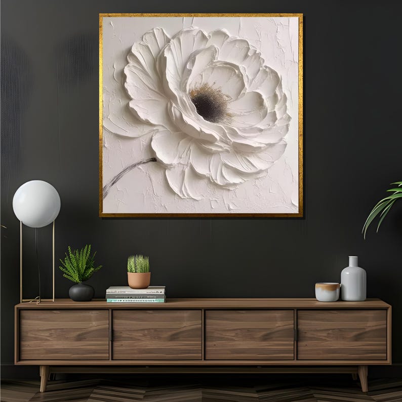 May include: A framed canvas print of a white flower with a textured, 3D effect. The flower is the focal point of the image, with a white background and a gold frame.