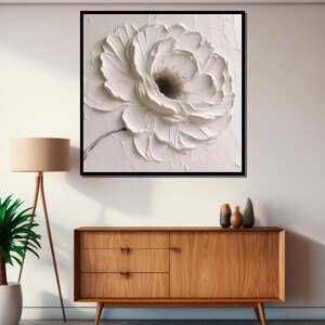 May include: A white flower with textured petals, painted in a 3D style on a white canvas. The flower is framed in a black frame.