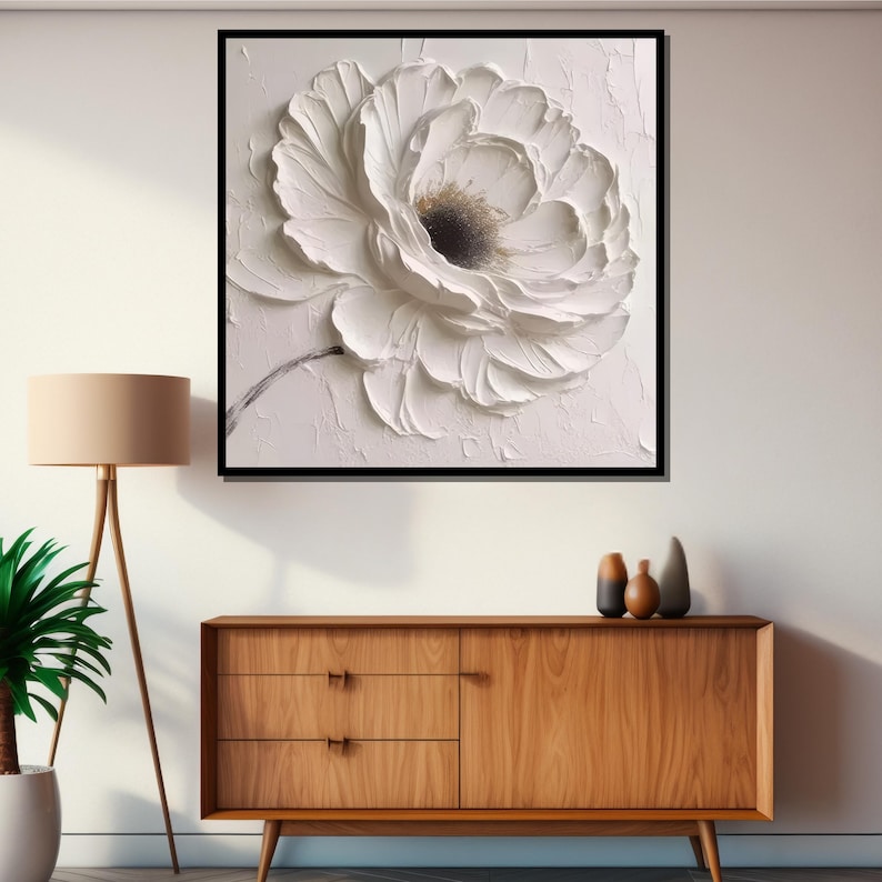 May include: A white flower with textured petals, painted in a 3D style on a white canvas. The flower is framed in a black frame.