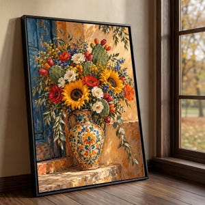 Puede incluir: Una impresión artística enmarcada que muestra un vibrante arreglo floral en un jarrón de cerámica decorativo. El ramo presenta girasoles amarillos brillantes, amapolas rojas, flores blancas y hojas de cactus verdes. El jarrón tiene patrones.