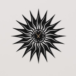 May include: Black sunburst wall clock with a round clock face featuring Roman numerals and gold hands. The clock is mounted on a white wall. Decorative items are on a wooden cabinet below the clock.