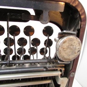 May include: Close-up of an antique typewriter's interior, showcasing the mechanical components. The image highlights the keys, levers, and metal parts, with a focus on the circular key tops and the intricate mechanics.