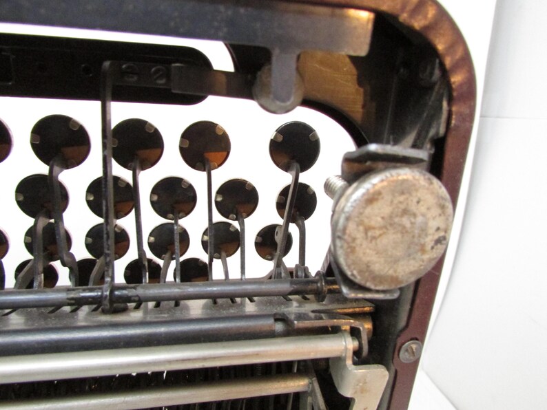 May include: Close-up of an antique typewriter's interior, showcasing the mechanical components. The image highlights the keys, levers, and metal parts, with a focus on the circular key tops and the intricate mechanics.