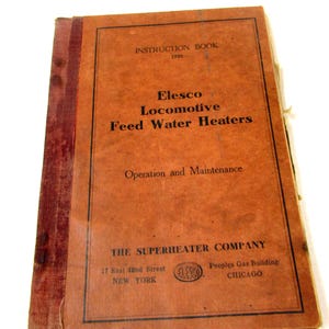 May include: A vintage instruction book for Elesco Locomotive Feed Water Heaters from 1936. The cover is a faded orange with black text and a black border. The book's title and company information are clearly visible.