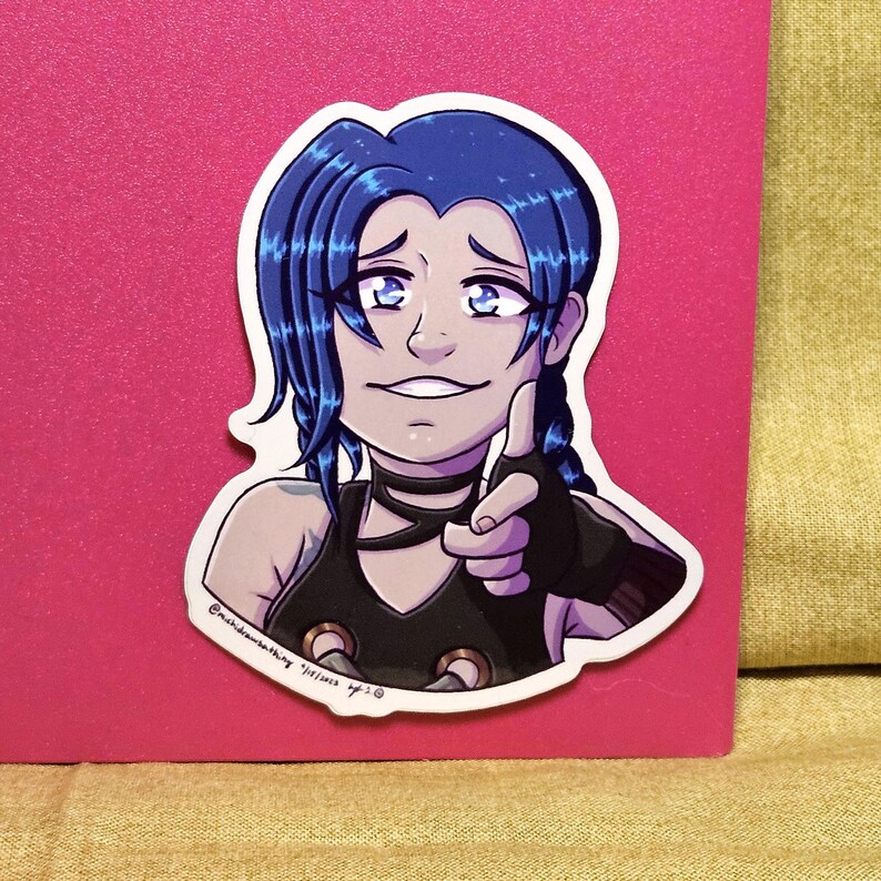 May include: A sticker featuring a cartoon illustration of a character with blue hair in braids, wearing a black top and choker, pointing with a gloved hand. The sticker has a white border and is set against a pink background.