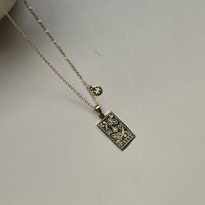 May include: Gold chain necklace with a pendant featuring a zodiac sign, Pisces, with a small star charm.