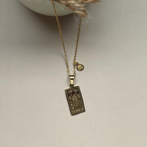 May include: Gold necklace with a pendant featuring a zodiac sign, Scorpio, and a small charm with the letter 'm'.