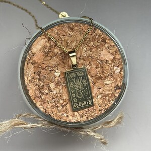 May include: Gold necklace with a gold pendant featuring a scorpion and the word "SCORPIO".