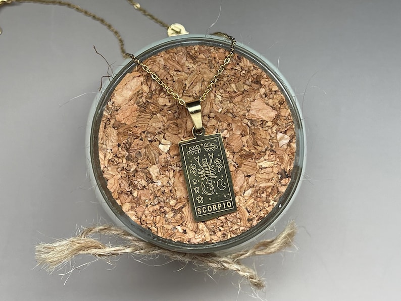 May include: Gold necklace with a gold pendant featuring a scorpion and the word "SCORPIO".