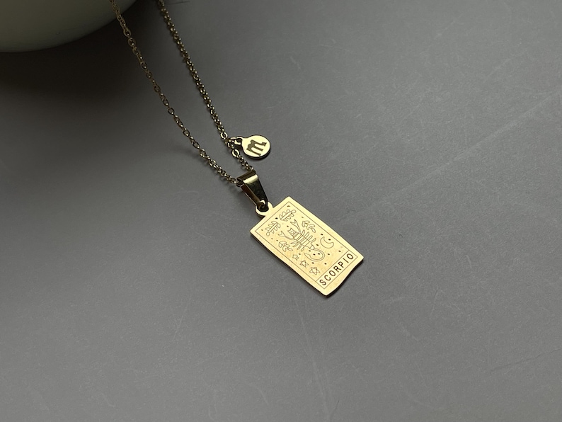 May include: Gold necklace with a pendant featuring a zodiac symbol and the word "SCORPIO".