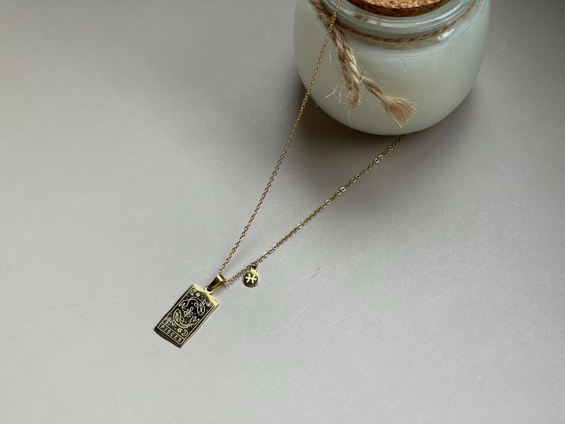 May include: Gold necklace with a Pisces zodiac sign pendant and a small star charm.