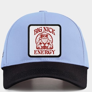 May include: A light blue and black baseball cap with a square patch showing a Santa Claus graphic. The patch reads "BIG NICK ENERGY" in red and white. The cap has a curved peak and a snapback fastening.