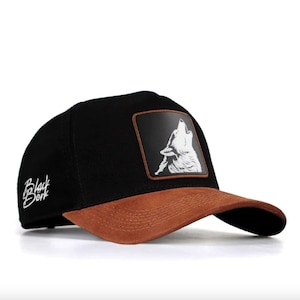 May include: Black baseball cap with a brown suede brim and a white wolf howling graphic on the front. The cap has "Black Bork" embroidered on the side.