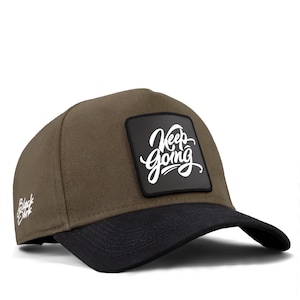 May include: A green and black baseball cap with a black square patch that says "Keep Going" in white lettering.