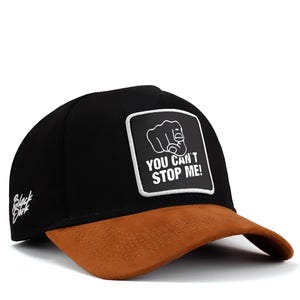 May include: Black and brown baseball cap with a white patch that says "YOU CAN'T STOP ME!" and a fist pointing forward.