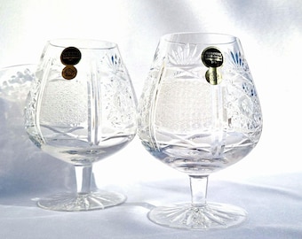 May include: Two clear glass brandy snifters with intricate cut designs. Each glass has a gold label with the text "Alexander Crystal Bohemia" and a diamond logo.