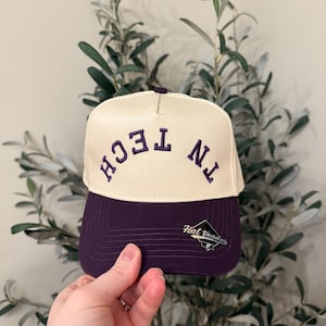May include: Cream-colored baseball cap with a purple brim and embroidered text "TN TECH". The hat features the "Hat Vendor" logo on the side. A stylish accessory for sports fans.
