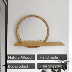 May include: A round wooden mirror with a shelf. The mirror is set in a circular frame and is attached to a rectangular shelf. The wood has a natural finish. The words "Natural Wood", "Handmade", and "Eco product" are visible.