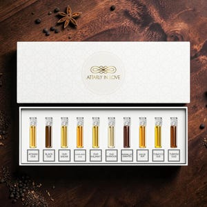 May include: A white rectangular gift box containing ten small glass vials of perfume, each with a label. The labels read Afghan Oud, Black Oud, Oud Badar, Himalayan Oud, Oud Kalimat, Oud Khanoor, Mukhallat Emirates, Oud De Nuit, Tobacco Oud, and Turkish Oud.