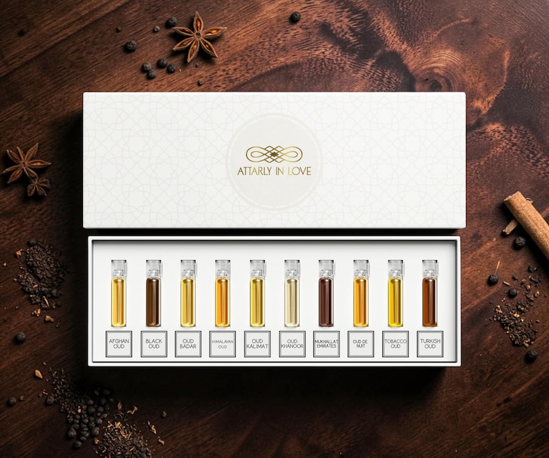 May include: A white rectangular gift box containing ten small glass vials of perfume, each with a label. The labels read Afghan Oud, Black Oud, Oud Badar, Himalayan Oud, Oud Kalimat, Oud Khanoor, Mukhallat Emirates, Oud De Nuit, Tobacco Oud, and Turkish Oud.
