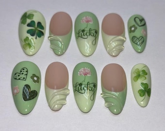 May include: Ten green and white nail wraps with various designs, including shamrocks, hearts, and the word "Lucky".