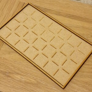May include: A wooden tray with a grid pattern of square compartments. The tray is made of light brown wood and has a natural finish.