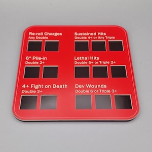 May include: Red and white plastic board with black squares for tracking dice rolls. The board has text that reads "Re-roll Charges Any Double", "Sustained Hits Double 4+ or Any Triple", "6" Pile-in Double 2+", "Lethal Hits Double 5+ or Triple 2+", "4+ Fight on Death Double 3+", and "Dev Wounds Double 6 or Triple 3+".