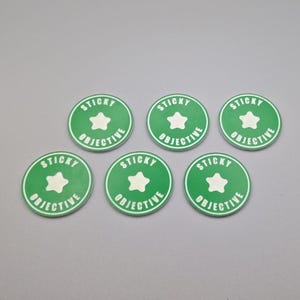 May include: Six green round stickers with white text that reads "STICKY OBJECTIVE" and a white star in the center.