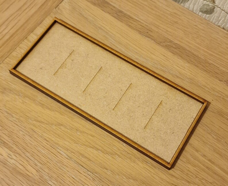 May include: A wooden tray with five slots, perfect for organizing small items. The tray is made of light brown wood and has a dark brown border.