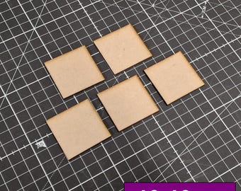 Op de afbeelding: Vijf vierkante, lichtbruine houten tegels, elk 40 mm x 40 mm groot, zijn gerangschikt op een zwarte snijmat met witte rasterlijnen. De tekst "40x40mm" staat in een paarse rechthoek rechtsonder.