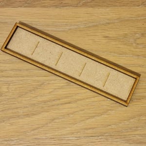 May include: A wooden tray with five slots for holding small items. The tray is made of light brown wood and has a natural finish.