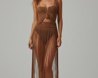 May include: A brown macrame dress with a crop top and a long fringe skirt. The top has a square neckline and a small cutout. The skirt is made of long, vertical fringe. The dress is a neutral color and appears to be handmade.