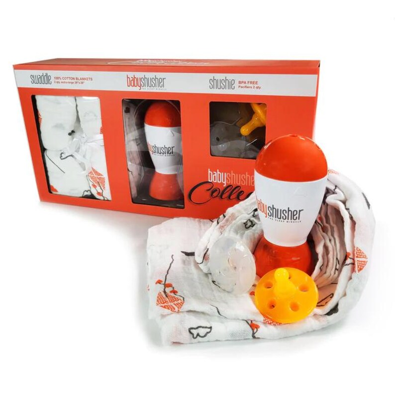 May include: An orange and white baby shusher with a pacifier and a white and orange swaddle blanket. The box is orange and white and has the words "babyshusher" and "shushie" printed on it.