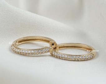 May include: A pair of gold hoop earrings with a double row of clear cubic zirconia stones.