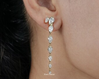 May include: Gold-toned drop earrings featuring a series of pear-shaped, clear gemstones. The earrings cascade down, with the largest stones at the top and gradually decreasing in size. The earrings are designed to be worn in the ear.