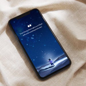 May include: A smartphone displaying a dark blue night sky with stars and a small figure standing on a hill. The text on the screen reads "Even the darkest nights are filled with stars waiting to be seen."
