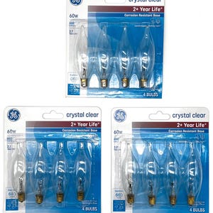 May include: Three packages of GE crystal clear 60W light bulbs. Each package contains four clear, flame-shaped bulbs with brass bases. The packaging is blue and white, with the text "crystal clear" and "2+ Year Life".