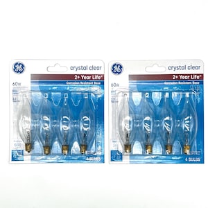 May include: Two packages of GE crystal clear light bulbs. Each package contains four bulbs, with a 60W rating and a 2+ year life. The packaging has a blue and white design with the GE logo.