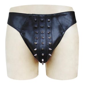 Puede incluir: Ropa interior de cuero negro con púas metálicas plateadas. La ropa interior tiene una cintura baja y una parte trasera de tanga. Las púas están dispuestas en filas verticales en la parte delantera.