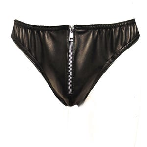 Puede incluir: Ropa interior negra con cremallera plateada en la parte delantera. El material es liso y brillante. La cremallera va de arriba a abajo. Estilo tanga.